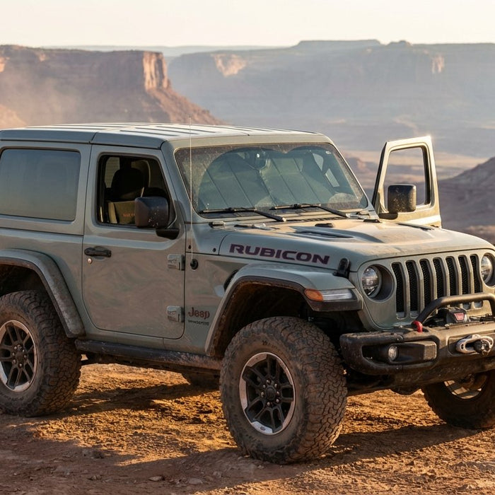 2019 Jeep Wrangler JL Rubicon on a red-rock desert trail at golden hour, trail bag on spare tire and Hothead headliner visible through the open door