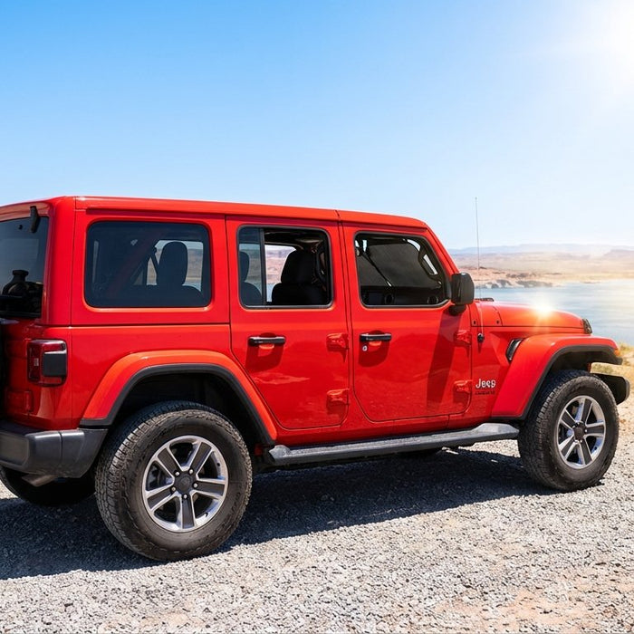 High-noon summer scene at a desert lake overlook — 4-door Jeep Wrangler JL with mesh sunshade deployed behind the windshield, loaded trail bag on spare tire, cooler and towel staged in the foreground