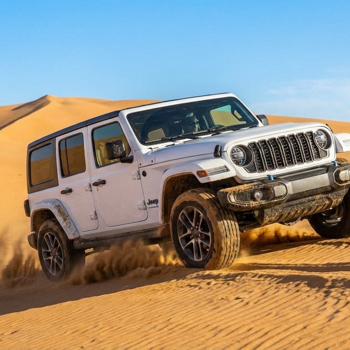 White 2024 Jeep Wrangler driving through sand dunes