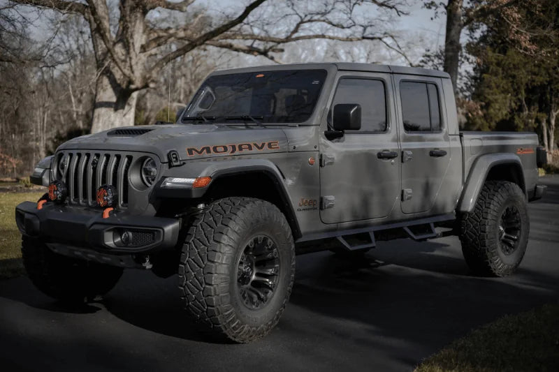 Gray Jeep Gladiator Mojave on black pavement with trees, showcasing Hothead Headliners for custom comfort and style (mobile version)